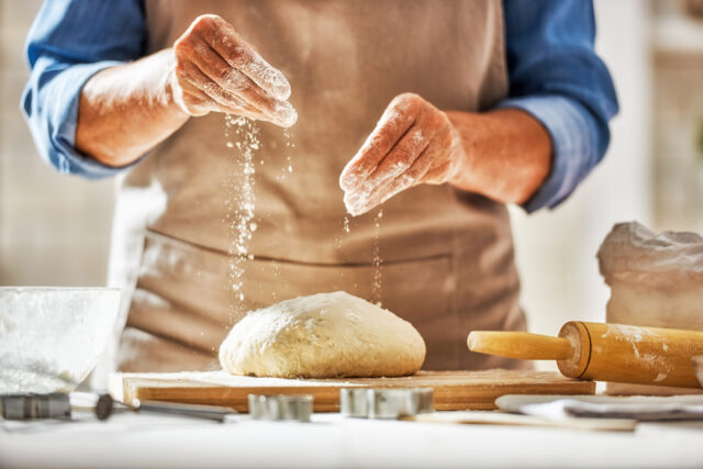 Close up view of baker is working. Homemade bread. Hands preparing dough on wooden table.