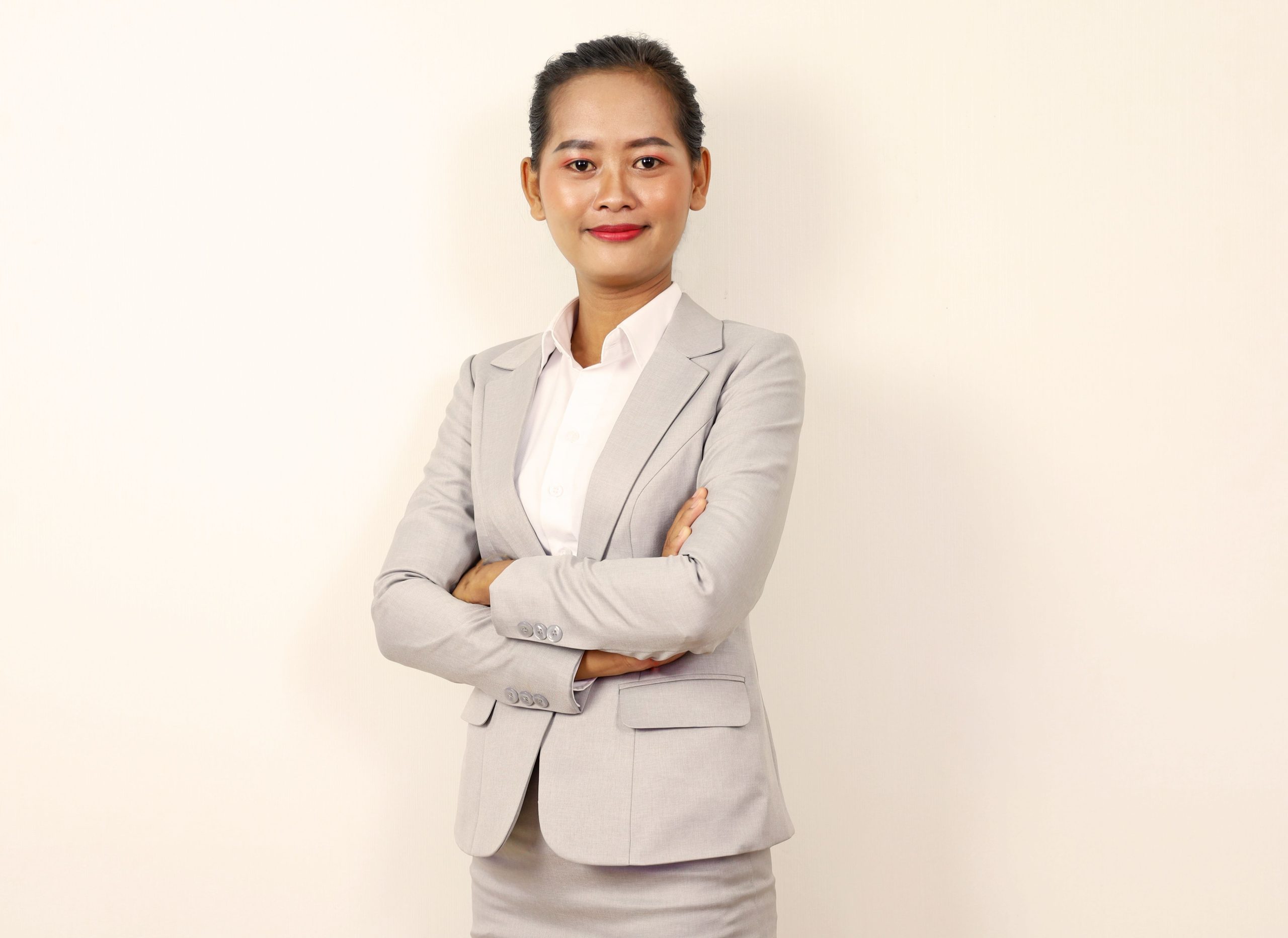Professional woman in a gray suit standing with crossed arms, exuding confidence and elegance