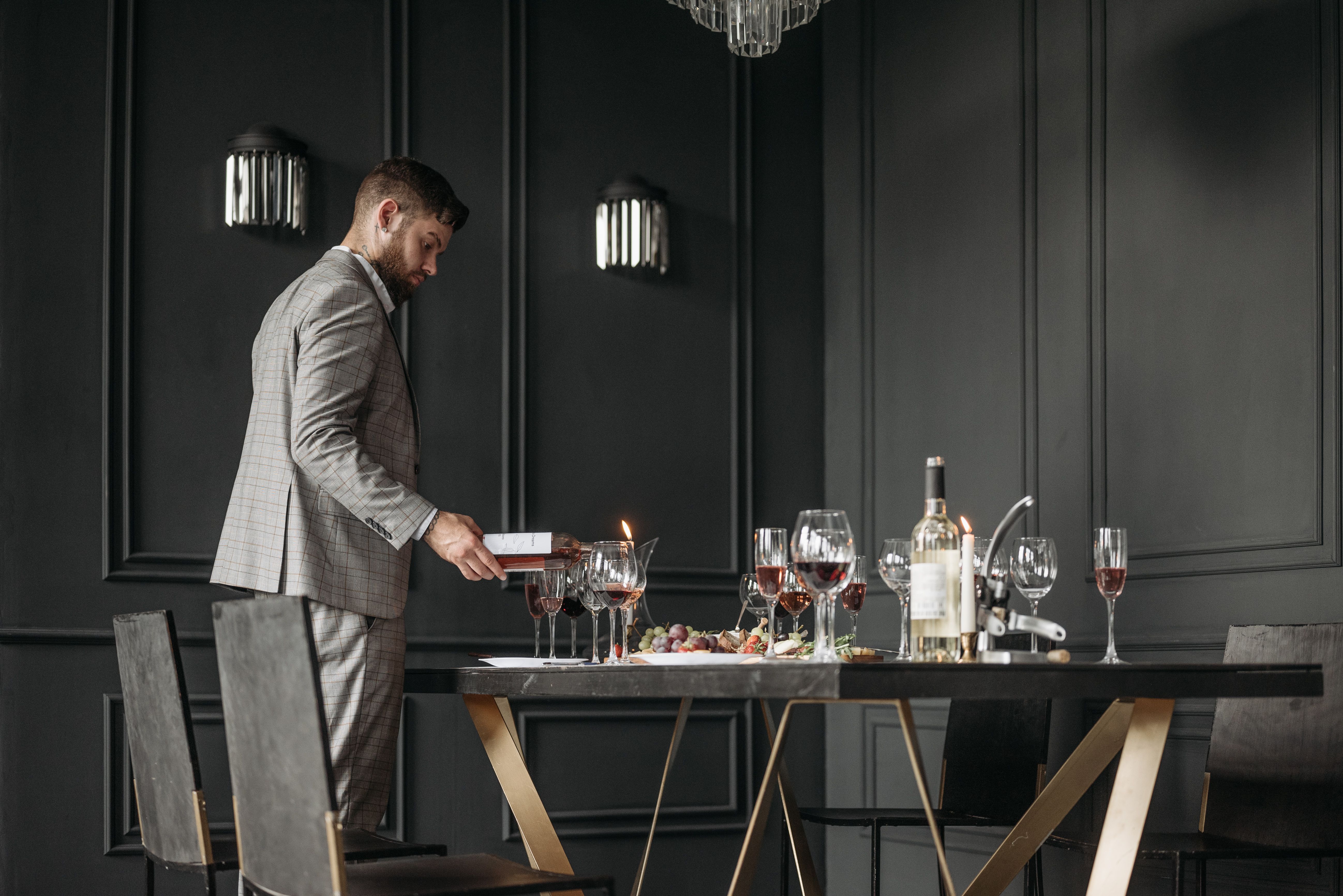 Sommelier preparing a wine tasting table with bottles and glasses in a stylish setting