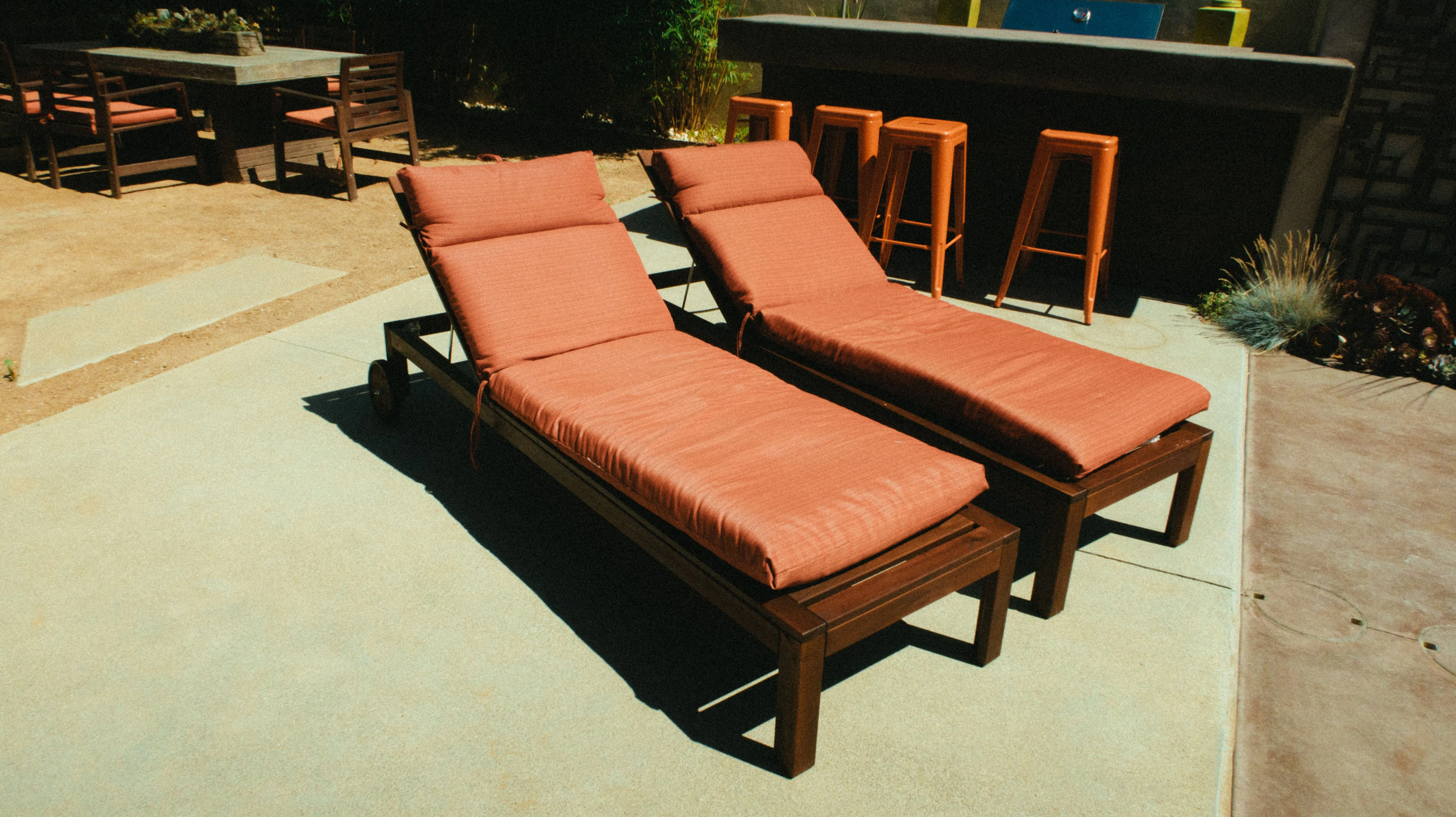 Stylish luxury backyard patio with modern wooden deck chairs and outdoor dining area
