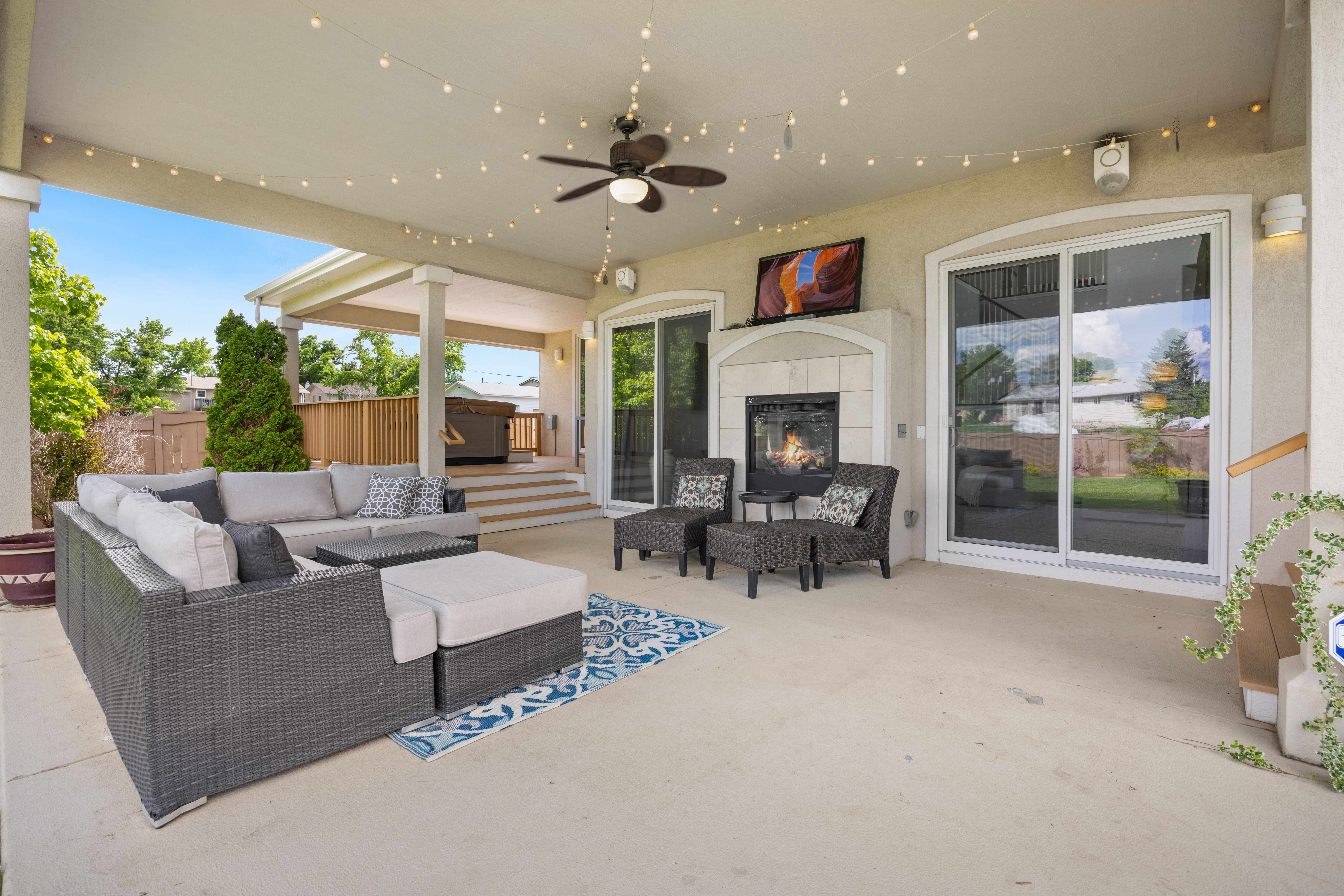 Luxurious outdoor patio with cozy fireplace, modern furniture, and ambient string lights