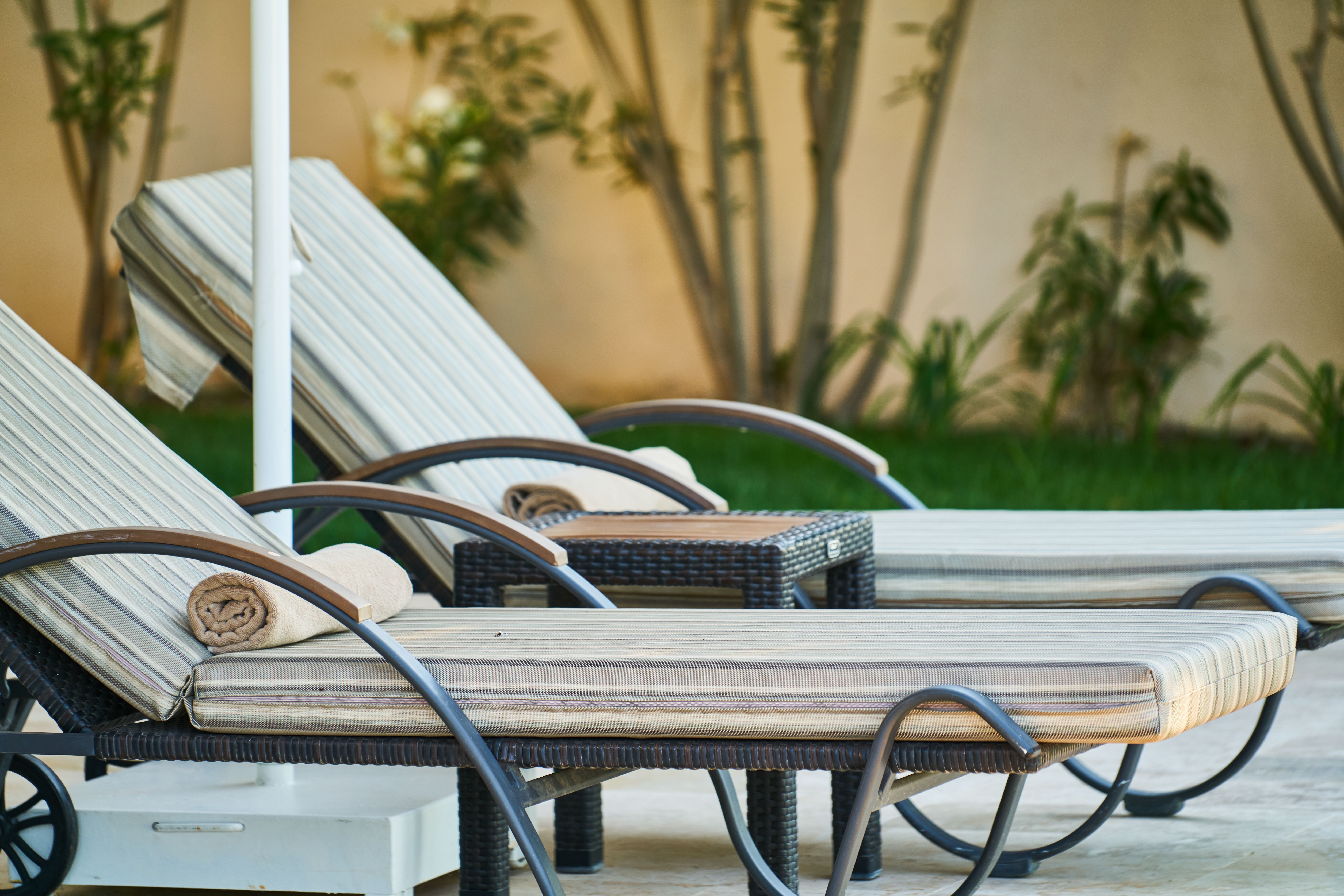 Elegant wooden sun loungers poolside at a luxury tropical celebrity-style resort